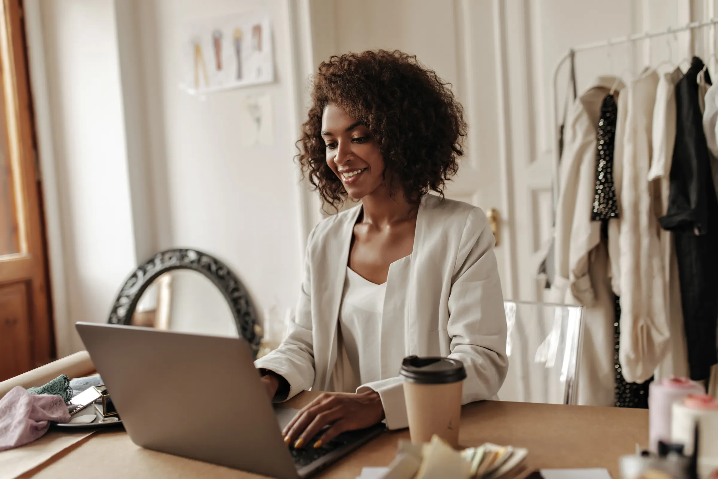 A designer at a laptop with sketches and a coffee, working through page concepts.