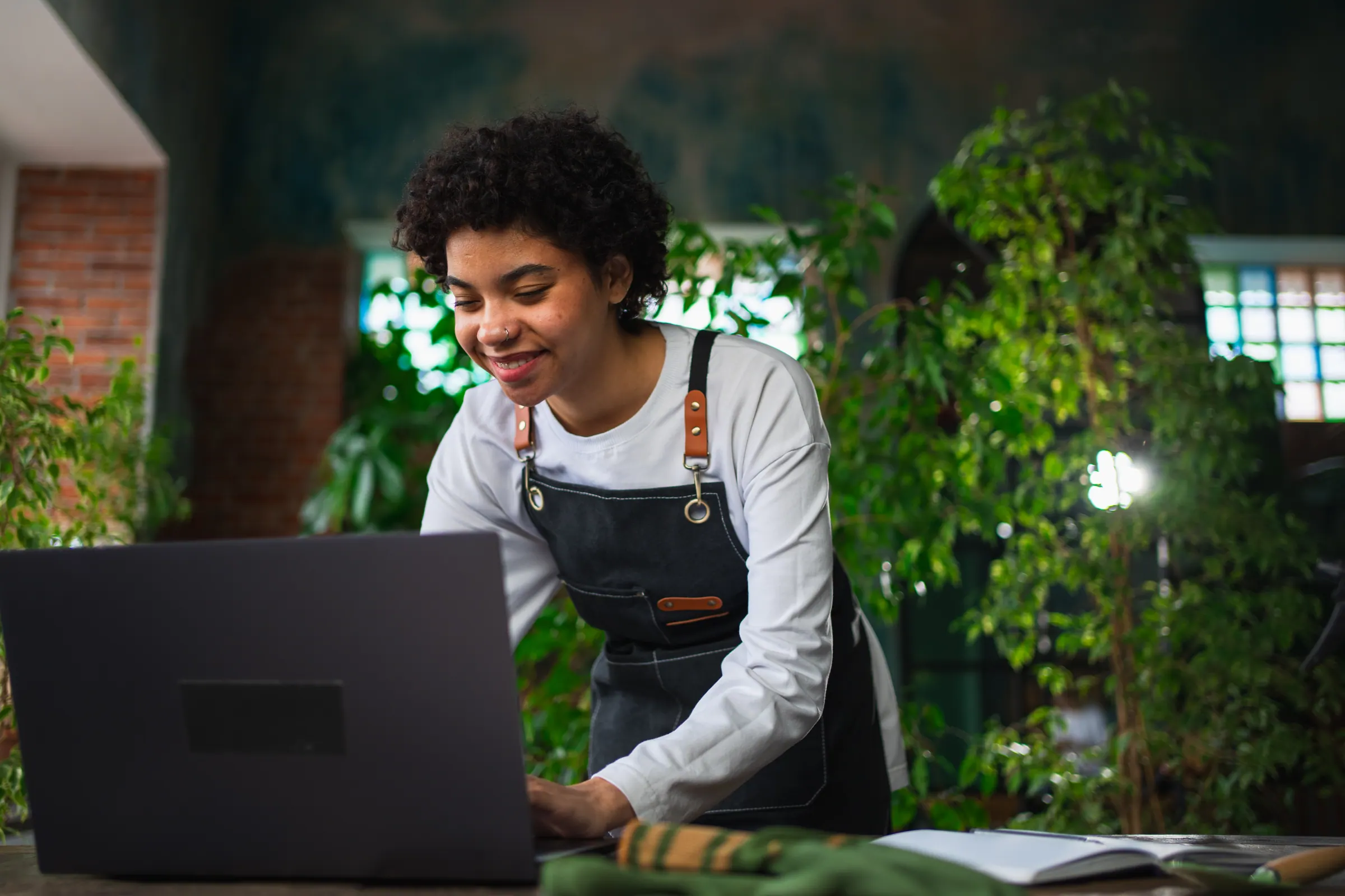 A local business owner working at a laptop in their storefront, processing online inquiries.