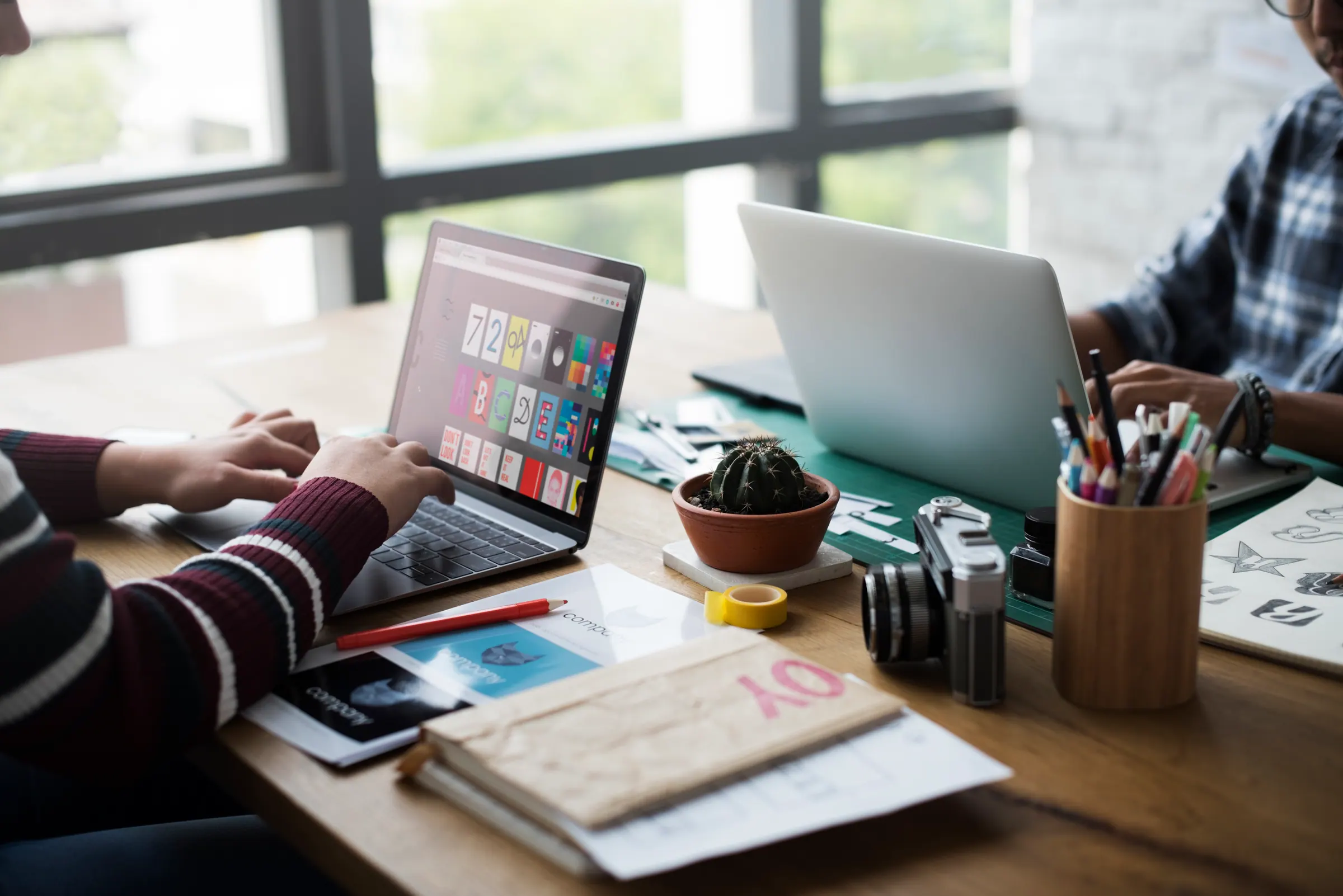 A small team collaborating around a laptop in a bright workspace.