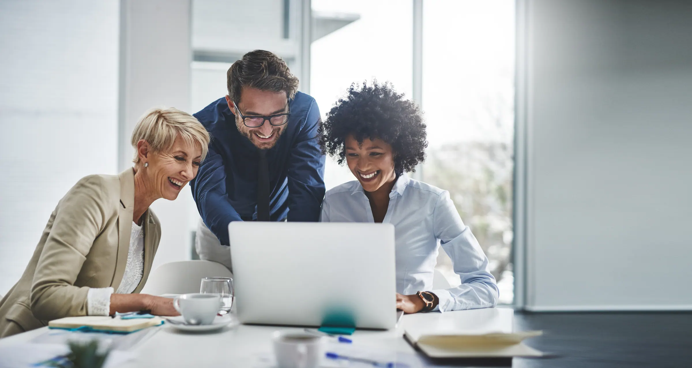 A small team huddled around a laptop in a bright workspace — the texture of doing the work together.