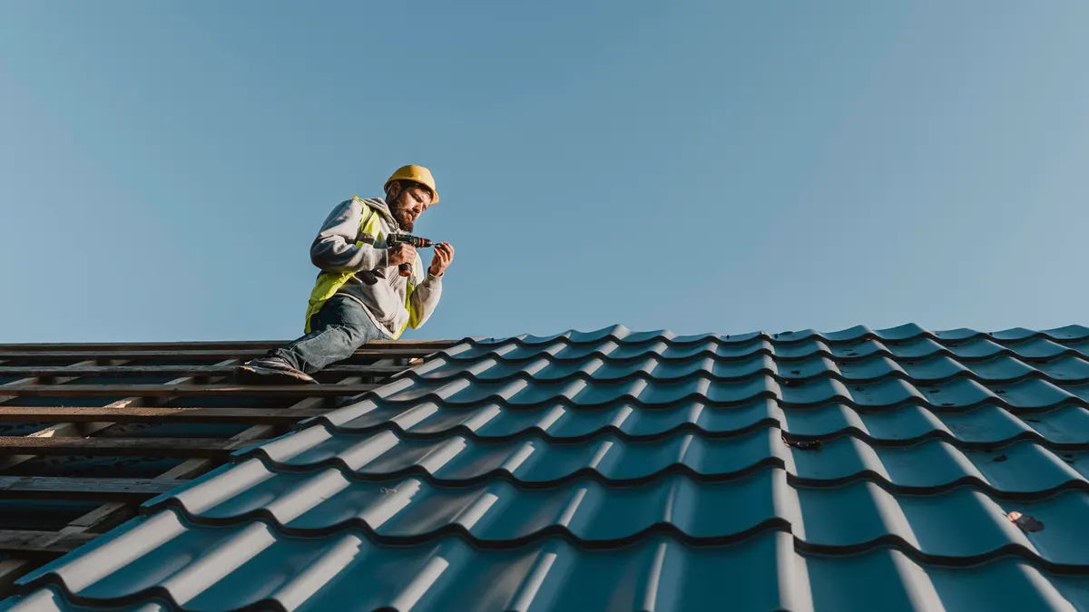 A roofer working on a residential roof — the trade hit hardest by the 2026 lead-cost crisis.